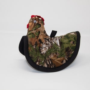 Peut inclure: Manchon de protection contre la chaleur en forme de poulet en tissu camouflage avec une crête rouge et un œil noir. Le manchon est bordé de noir.