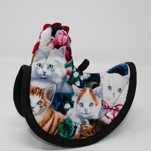 May include: A black and white cat-themed pot holder with a red, white, and blue floral design. The pot holder is shaped like a chicken.