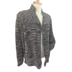 May include: A patterned jacket with a high collar. The jacket features a black, white, and burgundy chevron design. The open front jacket is displayed on a mannequin.