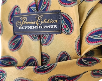 May include: A gold silk tie with a paisley pattern and the text "Premier Edition KUPPENHEIMER" on a black label.