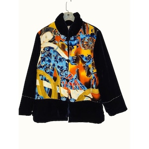 Puede incluir: Chaqueta de terciopelo azul marino oscuro con un panel frontal estampado y colorido. El panel presenta un diseño con elementos azules, amarillos, naranjas y blancos. La chaqueta tiene cuello mandarín y botones.