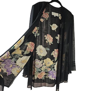 May include: Black sheer floral print cardigan with long sleeves and a tie closure. The cardigan is lined with a floral print fabric.