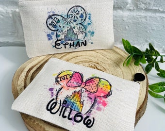 May include: Two personalized canvas zipper pouches with a watercolor design of Mickey Mouse ears. One pouch features a blue and white design with the text "2023 EPHAN" and the other pouch features a rainbow design with the text "2023 WILLOW".