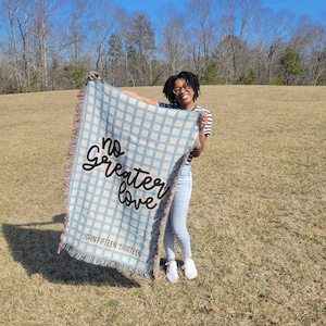 May include: A blue and white checkered woven throw blanket with the text "No greater love John Fifteen Thirteen" in black lettering.