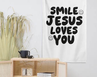 May include: White tapestry with black text that reads "Smile Jesus Loves You" with a smiley face on either side of the text.