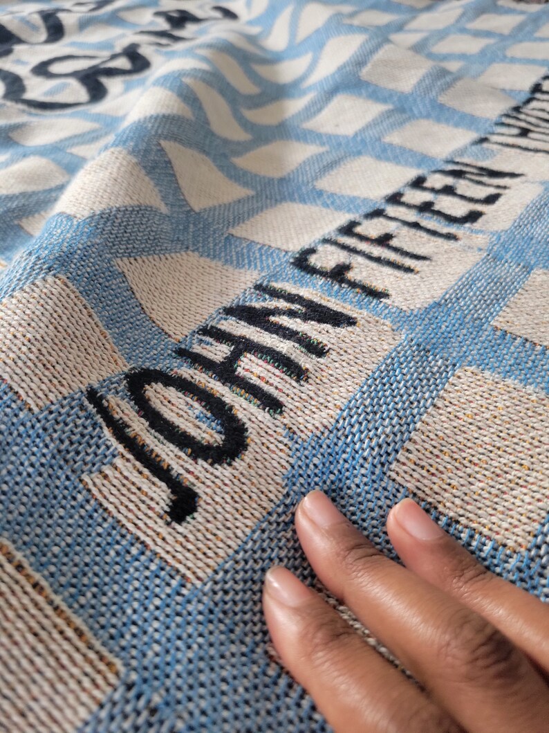 May include: A blue and white woven throw blanket with the text "JOHNNY FIFTEEN" woven into the fabric.