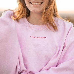 May include: A pink sweatshirt with the text "I shall not want" embroidered in red on the front.
