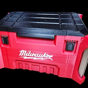 May include: A red and black Milwaukee tool box with the Milwaukee logo in white. The tool box has a textured black lid and red body. The box has two black latches and two red side handles. The tool box is designed to store tools.