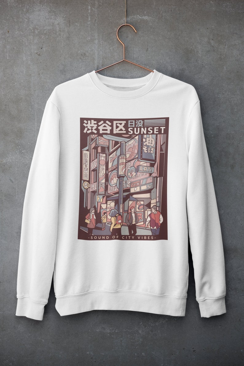 May include: White sweatshirt with a graphic print of a city street scene at sunset. The graphic features a Japanese cityscape with neon signs and people walking. The text "渋谷区日没 SUNSET" is printed above the graphic. The text "SOUND OF CITY VIBES" is printed below the graphic.