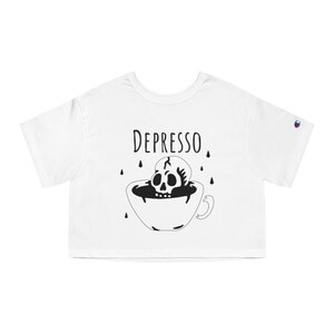 May include: White cropped t-shirt with a black and white illustration of a skull in a coffee cup. The text "DEPRESSO" is above the illustration.