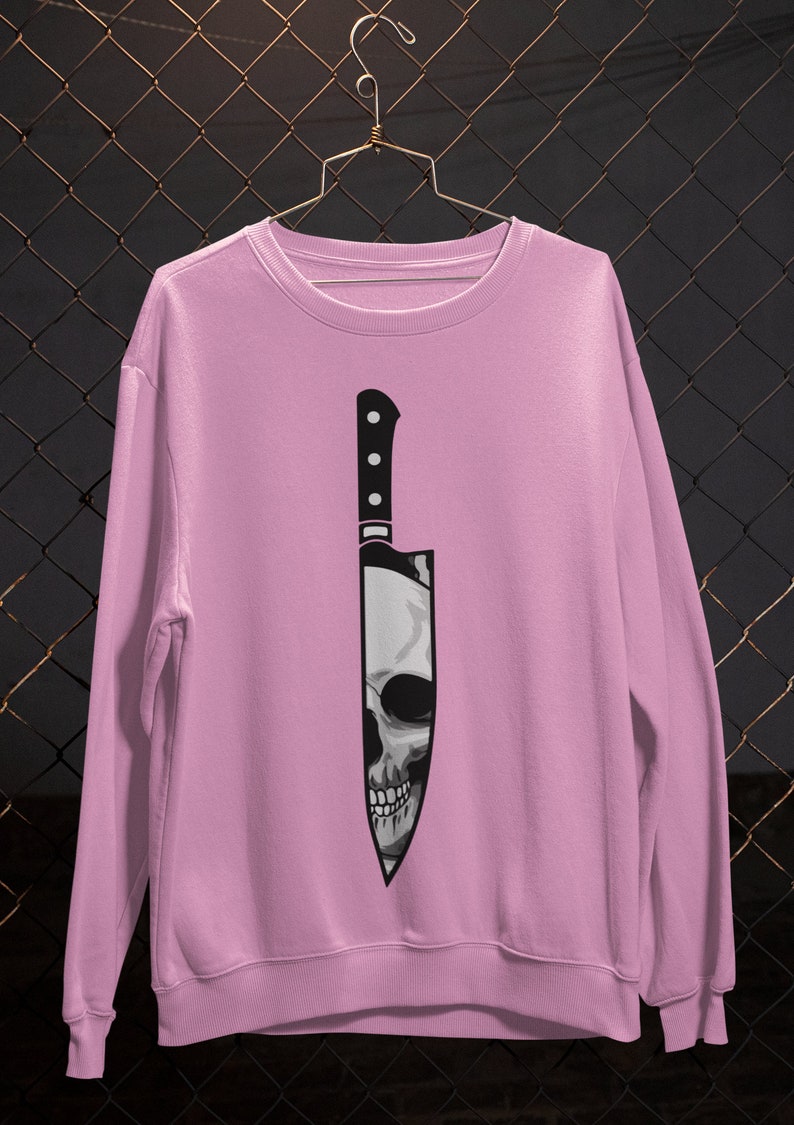 May include: A pink sweatshirt with a graphic of a black knife with a skull inside.