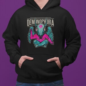 May include: Black hooded sweatshirt with a pink and blue demon graphic and the text "DEMONOPHOBIA" in white.