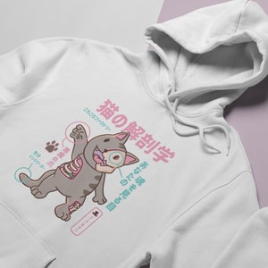 May include: White hoodie featuring a cartoon cat illustration. The cat is dissected with Japanese text that reads "Cat Anatomy" and "See your soul".