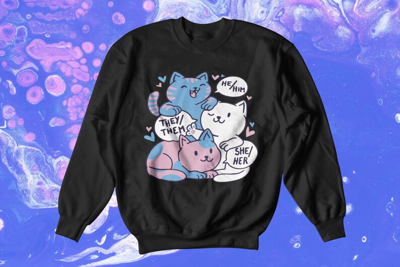 May include: Black sweatshirt with a graphic of three cats stacked on top of each other. The cats are wearing different colored collars and have speech bubbles above their heads. The speech bubbles say "They/Them", "He/Him", and "She/Her".