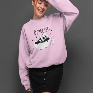 May include: A pink sweatshirt with the text "DEPRESSO" and a black and white illustration of a skull in a coffee cup.