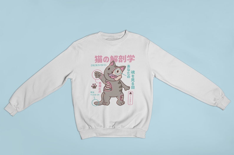 May include: White sweatshirt featuring a cartoon cat illustration. The cat is grey with pink accents and has a skeleton inside. The text on the sweatshirt is in Japanese and reads "Cat Anatomy".