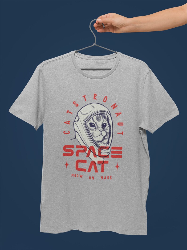 May include: A gray t-shirt with a graphic of a cat wearing an astronaut helmet. The text on the shirt reads "Catstronaut Space Cat Meow On Mars".