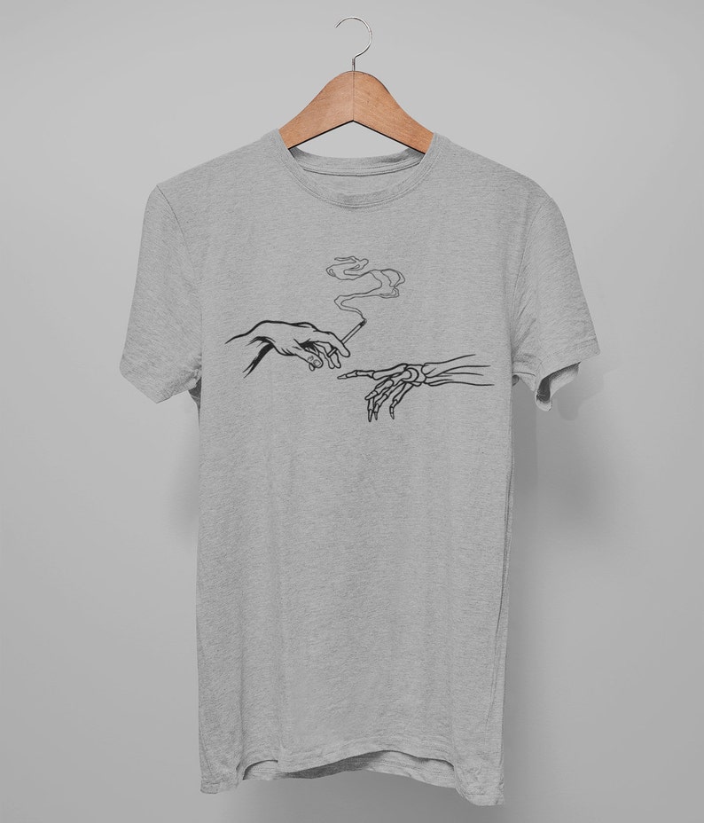 May include: A heather grey t-shirt with a black and white graphic of two hands reaching towards each other, one human and one skeletal, passing a cigarette.