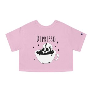 May include: Pink cropped t-shirt with a black and white illustration of a skull in a coffee cup. The text "DEPRESSO" is printed above the illustration.