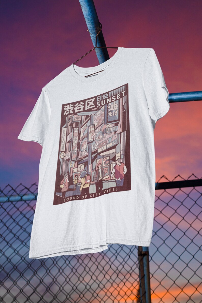 May include: White t-shirt with a graphic print of a city street scene at sunset. The graphic features buildings with Japanese text and the words "Sunset" and "Sound of City Vibes".