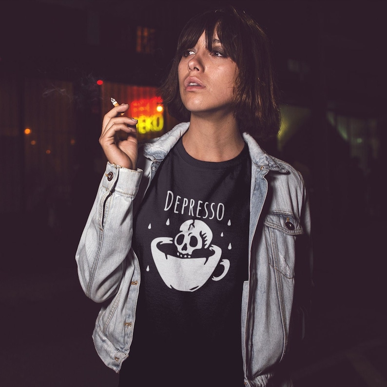 May include: A black t-shirt with a white graphic of a skull in a coffee cup with the text "Depresso" above it.