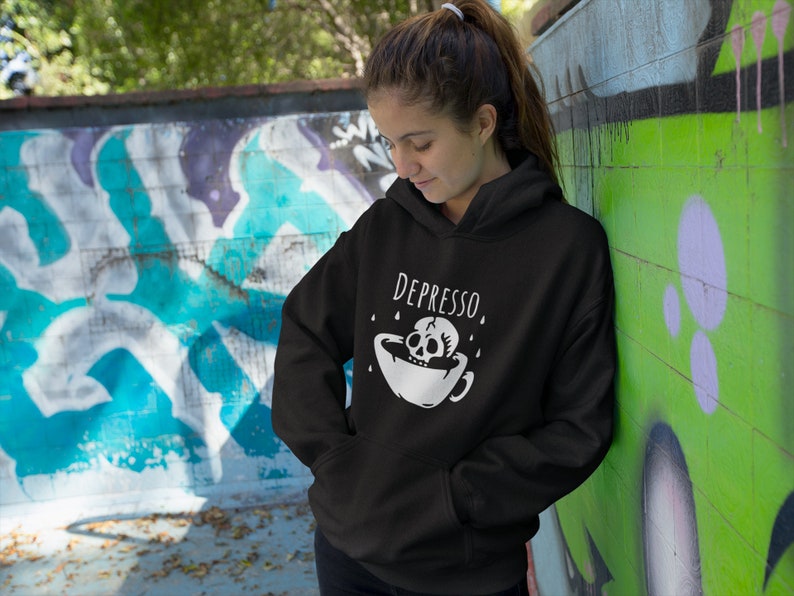 May include: Black hoodie with a white skull and crossbones graphic and the text "DEPRESSO" printed on the front.