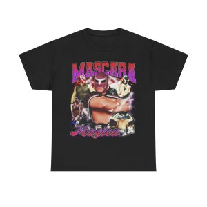 May include: Black t-shirt with a vintage-style graphic of a wrestler wearing a pink and purple mask. The graphic says "Mascara Magica" in a purple and pink font.