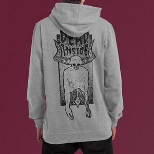 Pode incluir: Uma camisa de moletom cinza com capuz com uma estampa gr&aacute;fica em preto e branco de uma figura esquel&eacute;tica com chifres e o texto "DEAD INSIDE".