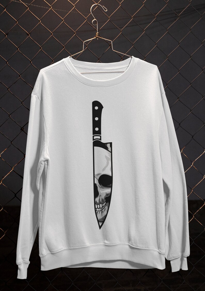May include: White sweatshirt with a black and white graphic of a skull inside a knife.
