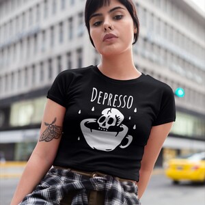 May include: Black t-shirt with a white graphic of a skull in a coffee cup with the text "Depresso" above it.