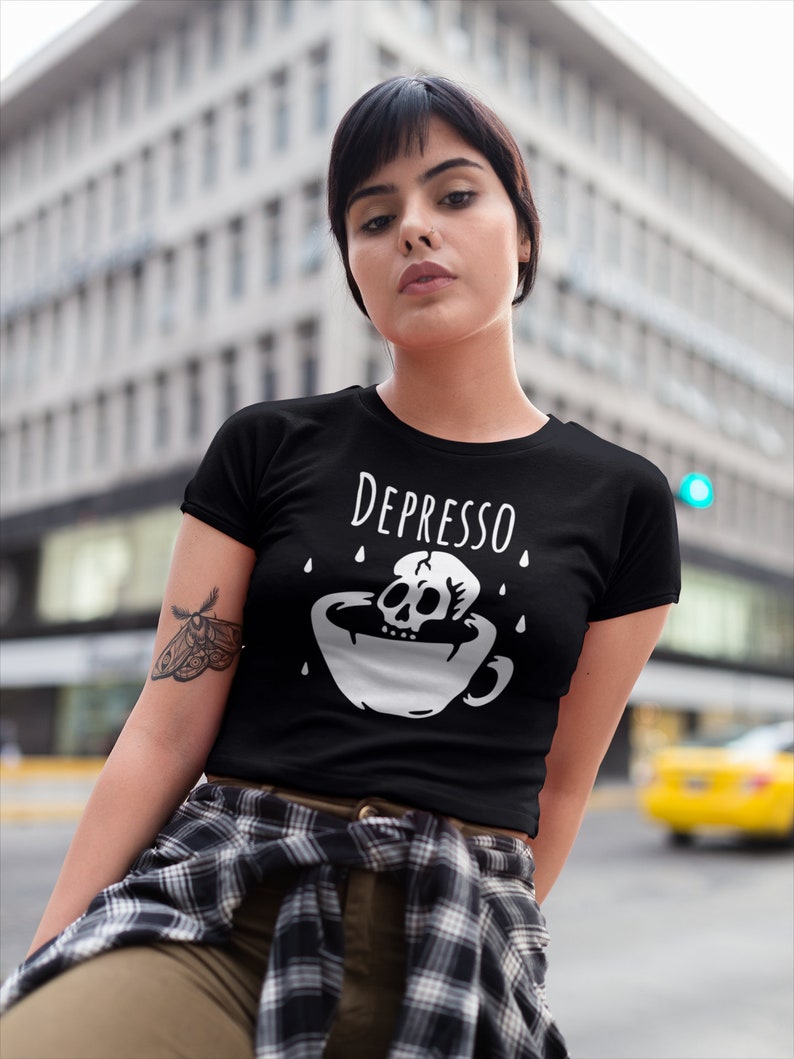 May include: Black t-shirt with a white graphic of a skull in a coffee cup with the text "Depresso" above it.