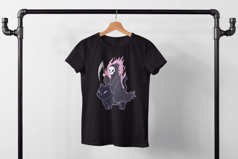 K&ouml;nnte beinhalten: Schwarzes T-Shirt mit einem Grafikdruck eines Skeletts in einer Kapuzenrobe, das auf einer schwarzen Katze reitet. Das Skelett h&auml;lt eine Sense und die Katze hat rosa Flammen um sich herum.