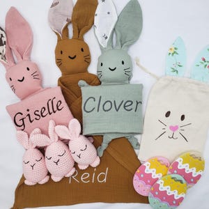 May include: Three personalized bunny blankets with the names Giselle, Clover, and Reid embroidered on them. The blankets are made of a soft, muslin fabric and are perfect for cuddling. The set also includes three crocheted bunny toys and two colorful Easter egg-shaped teethers.
