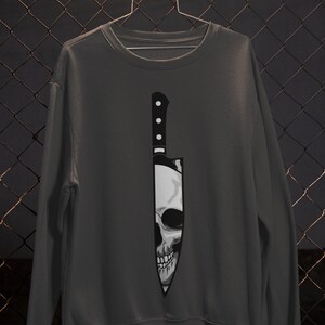May include: A dark gray sweatshirt with a graphic of a skull inside a knife.