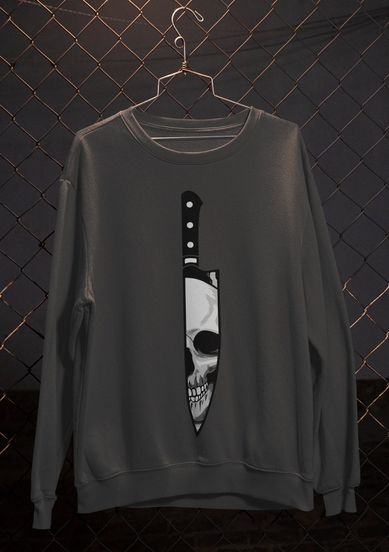May include: A dark gray sweatshirt with a graphic of a skull inside a knife.