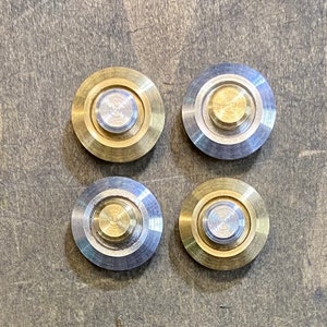 May include: Four round metal buttons with a silver center and a gold outer ring. The buttons have a raised center and a smooth surface.