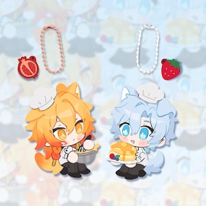 May include: Two cartoon chef characters, one orange and one blue, each holding food items. The orange character stirs a pot, while the blue character holds pancakes. A pomegranate and strawberry charm, and two beaded necklaces are also shown.