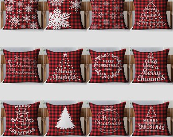 May include: A collection of twelve square throw pillows featuring a red and black buffalo plaid pattern. Each pillow displays white holiday-themed graphics, including snowflakes, Christmas trees, snowmen, and text such as Merry Christmas.