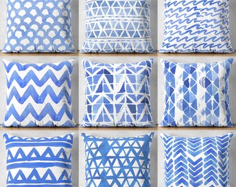 Könnte beinhalten: Neun blaue und weiße Kissen mit verschiedenen geometrischen Mustern. Die Muster umfassen Wellen, Zickzack, Dreiecke und Quadrate.