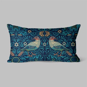 Peut inclure: Un coussin rectangulaire avec un fond bleu et un motif floral représentant deux oiseaux. Les oiseaux se font face et ont une palette de couleurs bleu clair et vert.