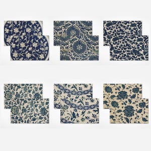 Può includere: Una collezione di sei set di tovagliette decorative. Ogni set presenta un design floreale o botanico unico in tonalità di blu e bianco. Le tovagliette sono rettangolari, alcune con angoli arrotondati.