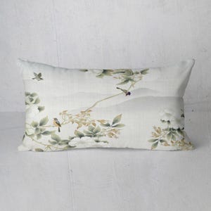 May include: Rectangular decorative pillow with a serene, watercolor-style design. The pillow features a light background with a landscape of mountains and branches with birds and white flowers. The color palette includes shades of green, white, and gray.