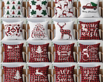 May include: A collection of sixteen square throw pillows featuring various Christmas-themed designs, including red and green trees, plaid leaves, reindeer, a truck, and holiday text like Joy, Merry Christmas, and Let it Snow on plaid backgrounds.
