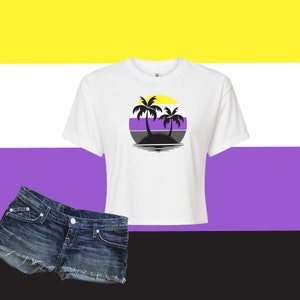 May include: White crop top with a circular graphic featuring two palm trees on an island, set against a yellow, white, purple, and black background. Denim shorts are in the lower left corner.