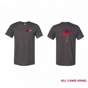 Op de afbeelding: Donkergrijze t-shirts met een rood bloemmotief op de rug en een kleine rode rechthoek op de voorkant. De tekst "HELL FLOWER APPAREL" staat onderaan de afbeelding.