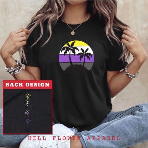 May include: Black t-shirt with a sunset graphic featuring palm trees and a purple, yellow, and white striped design. The back of the shirt has the text "love is love" written in purple and yellow.