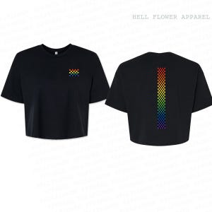 Pu&ograve; includere: Una t-shirt nera corta con un piccolo quadrato a scacchi arcobaleno sul petto sinistro e una lunga striscia verticale a scacchi arcobaleno sul retro. Il testo HELL FLOWER APPAREL &egrave; stampato nell'angolo in alto a destra dell'immagine.