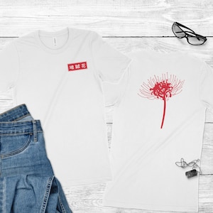 Op de afbeelding: Twee witte t-shirts met rode Japanse tekst en een rood bloemmotief. E&eacute;n shirt heeft de tekst in een rode rechthoek, de andere heeft een grote bloem op de rug. De shirts worden getoond met een blauwe jeans en accessoires.