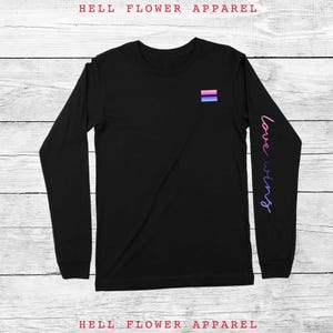 May include: Black long-sleeve t-shirt with a small bisexual pride flag on the left chest and the words "love wins" in a gradient of pink and purple on the right sleeve.