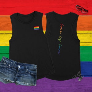 Può includere: Canotta nera senza maniche con una bandiera arcobaleno pride sul davanti e il testo "love is love" sul retro. La canotta è su uno sfondo di legno color arcobaleno.
